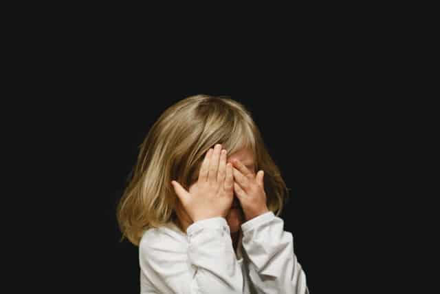 child covering her eyes - stress in children