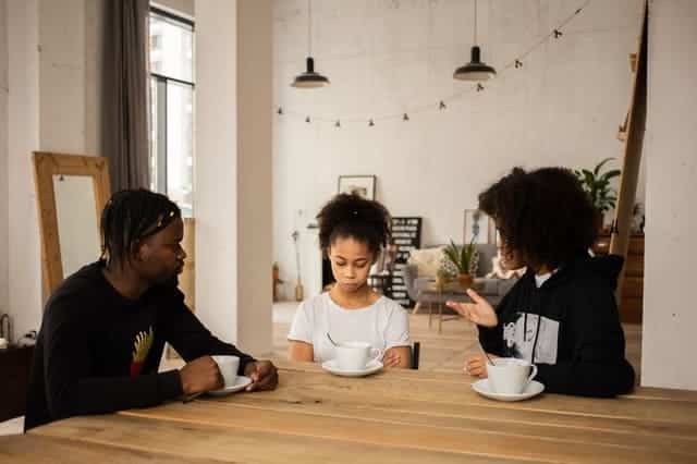 Parent with children at table - child with sad expression