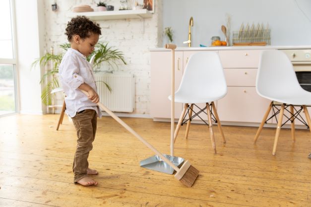 Child sweeping up mess - how to teach a child to take responsibility for their actions