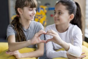 girls forming heart with hands - teaching kindness