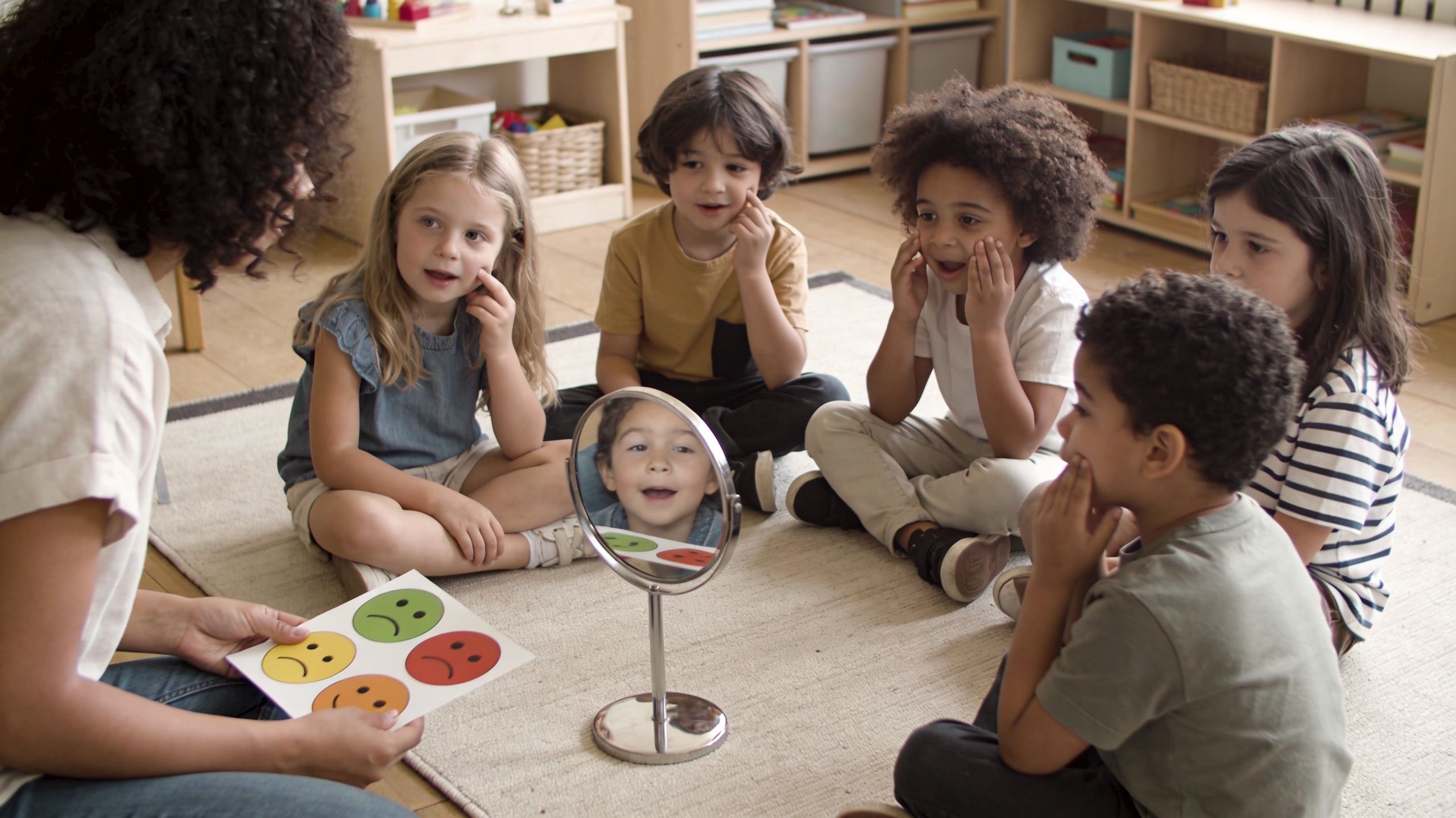 A teacher teaches preschoolers social skills by showing facial expression flashcards while children look in a mirror.